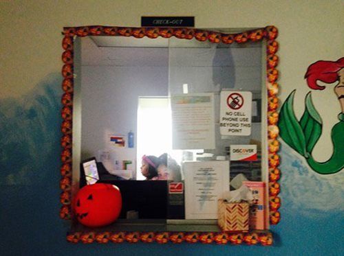 Decorative mirror with orange patterned frame, covered notices, and a red helmet or ball on a ledge