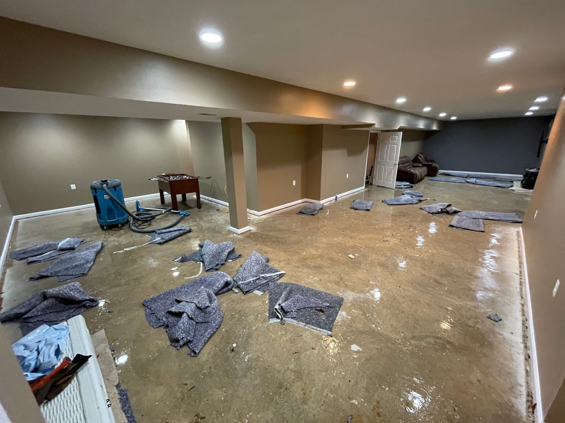 A flooded basement with a lot of blankets on the floor.