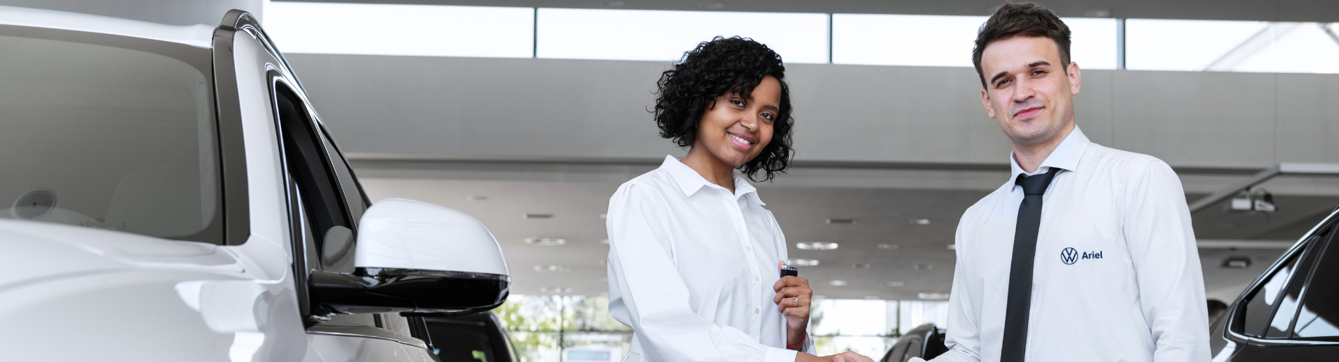 Um homem e uma mulher estão apertando as mãos na frente de um carro.