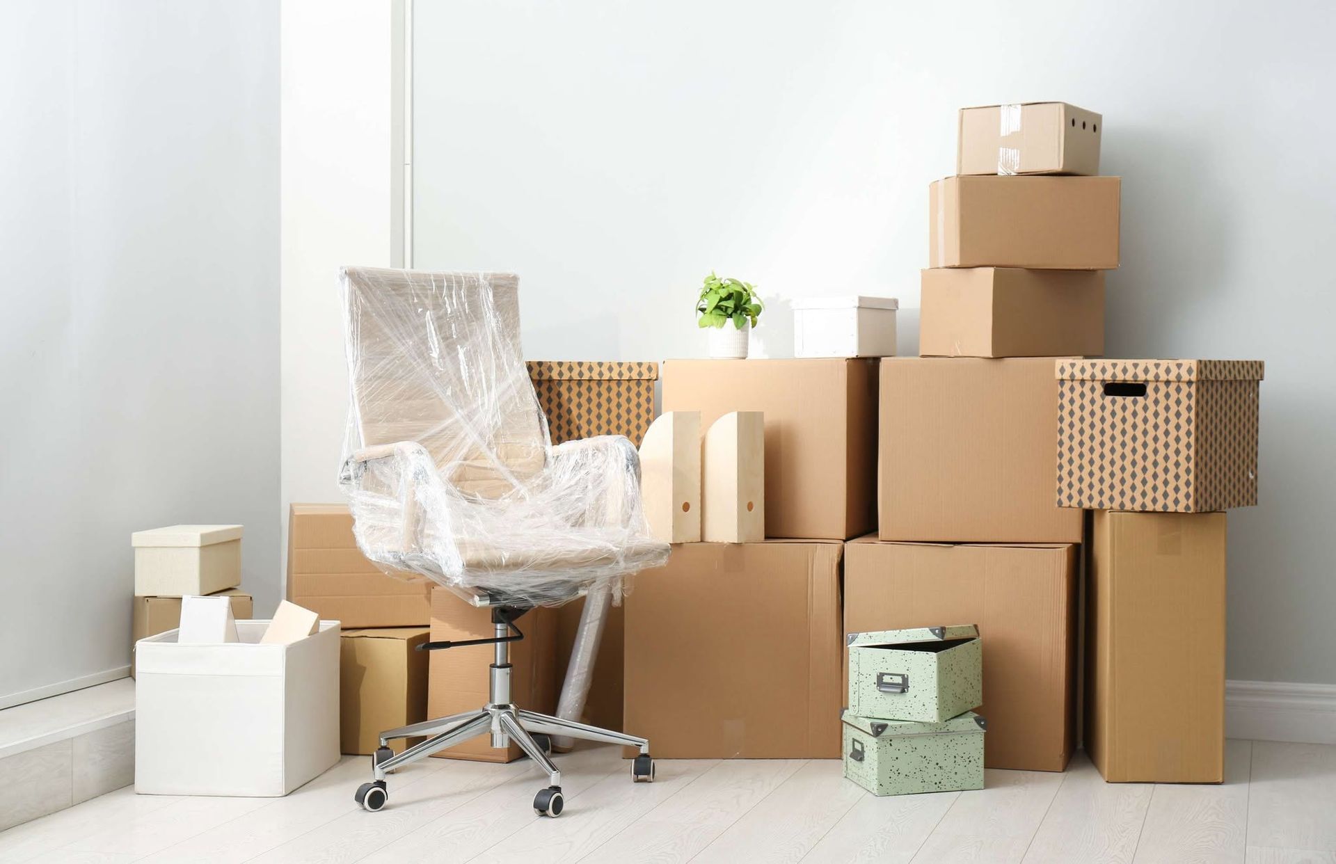 Packed moving boxes around a white office chair in a bright room