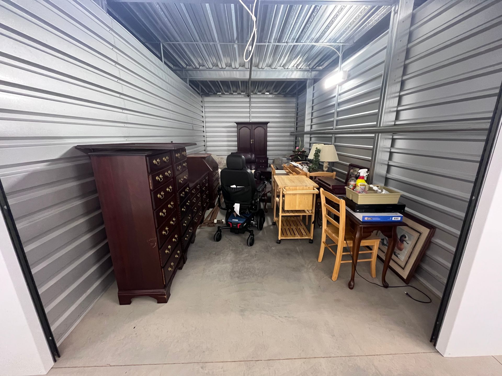Storage unit with furniture, boxes, and a person near the back wall