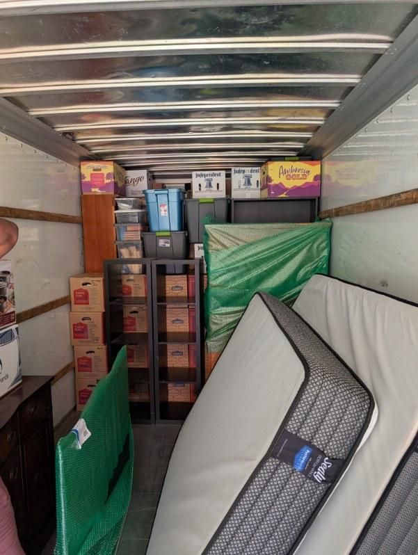 Stacked mattresses and boxed items inside a packed moving truck interior.