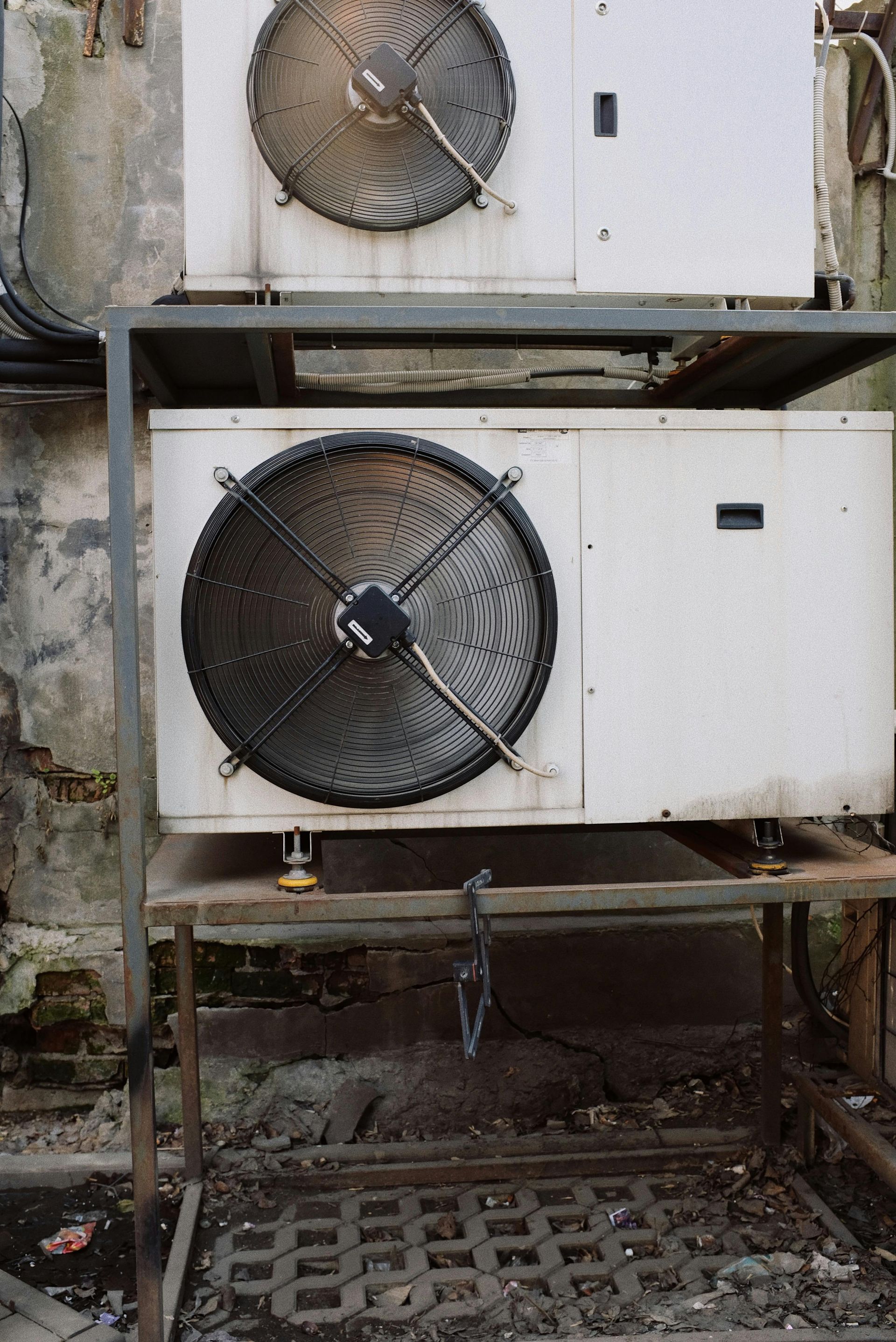 Two large industrial fans mounted on white outdoor HVAC units in a metal frame.