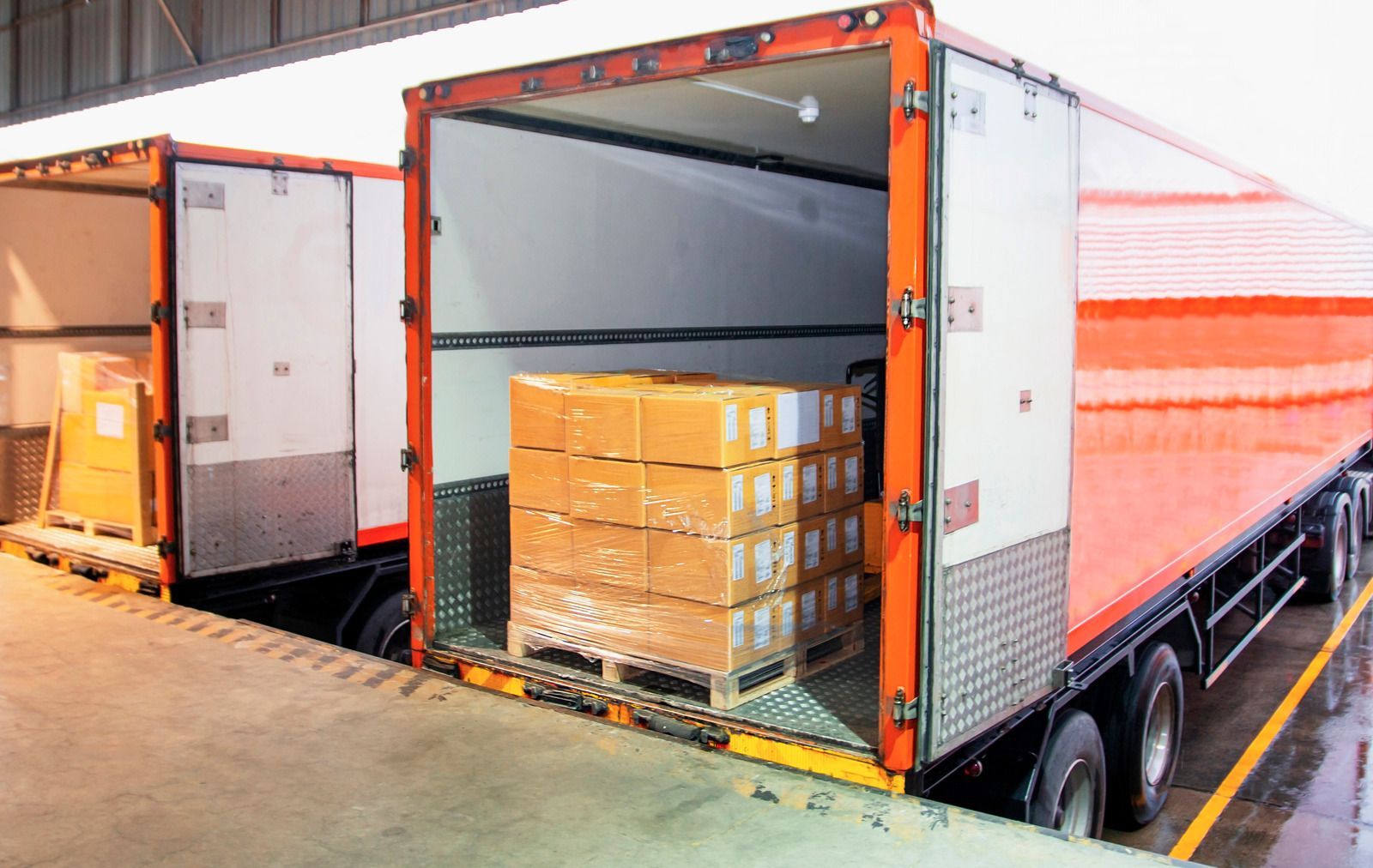 Open truck trailer loaded with stacked cardboard boxes at a warehouse dock