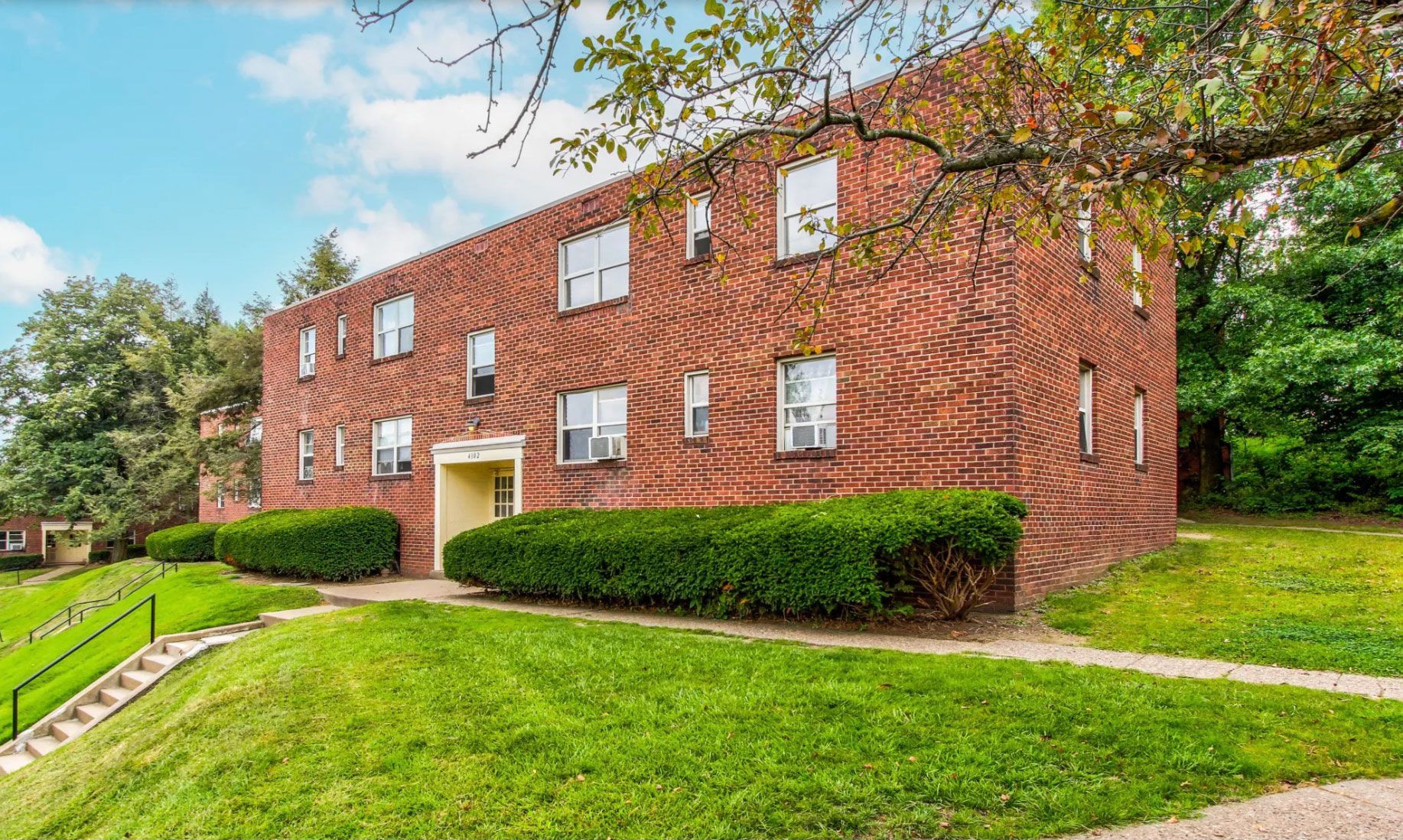 A large brick apartment building sitting on top of a grassy hill.