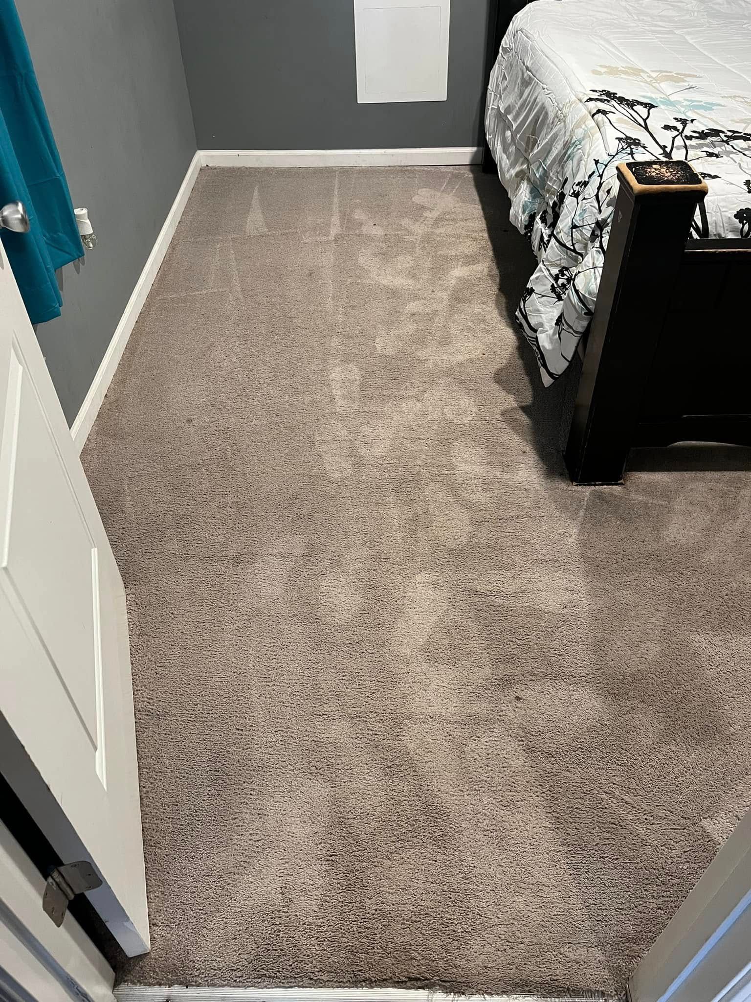 Carpeted bedroom with a bed on the right and a doorway on the left.