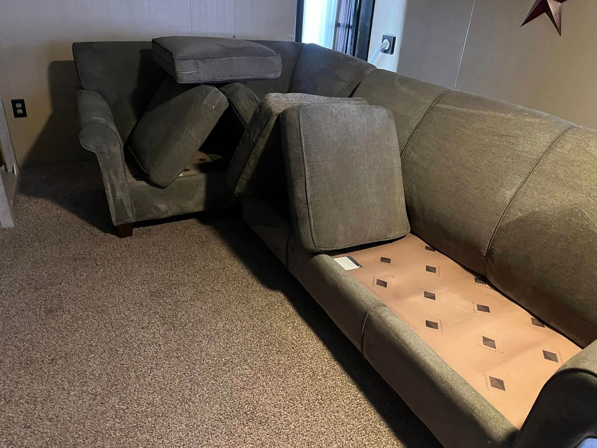 Collapsed sofa cushions in a living room, with seats and backrests fallen apart exposing the frame.