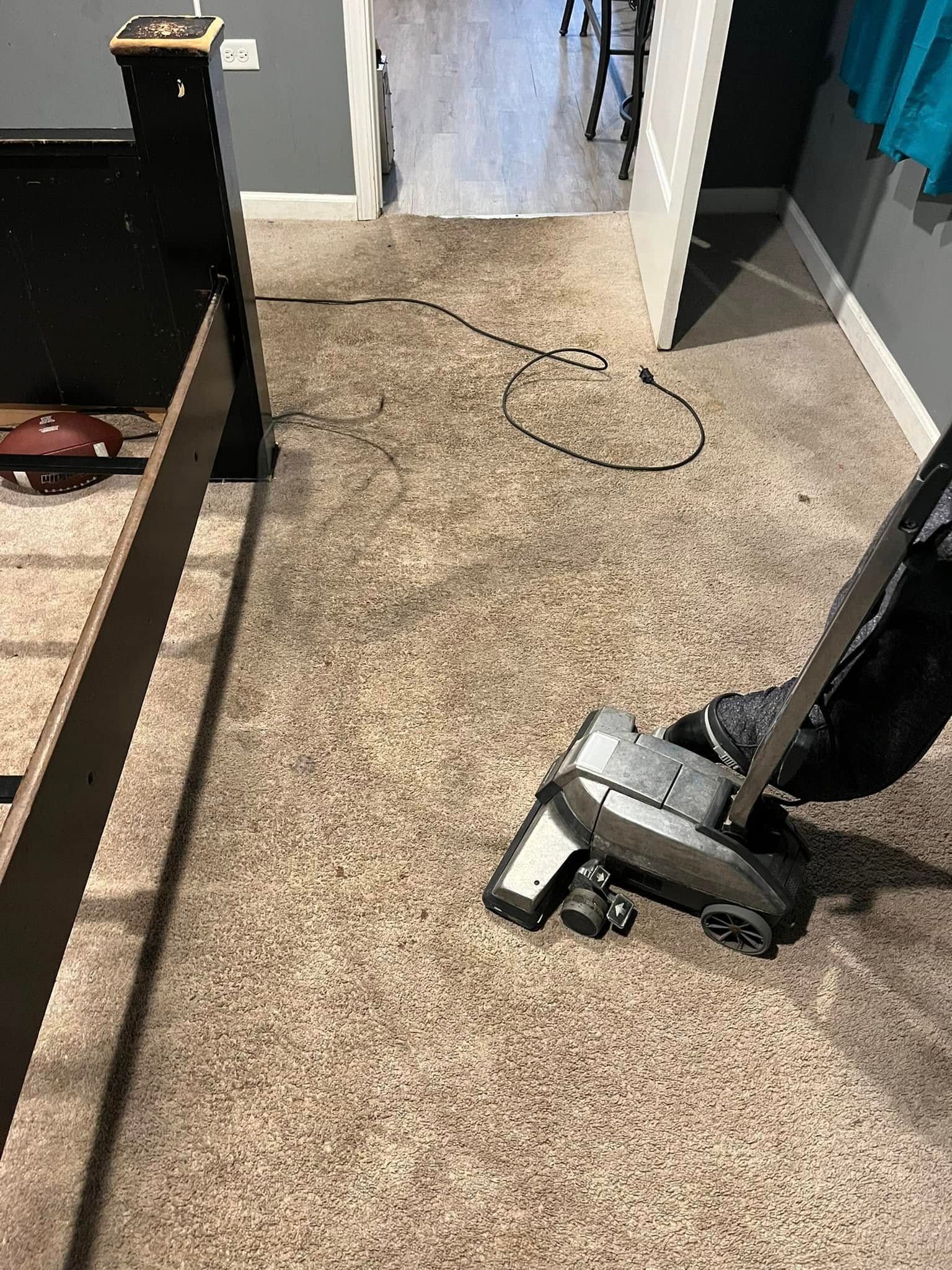 Carpeted room with a metal scooter-like device in the foreground and a cord on the floor near an open doorway.