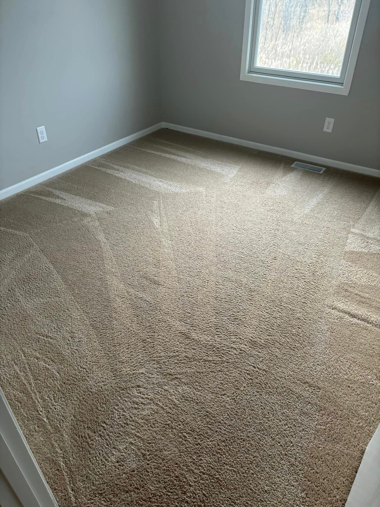 Empty carpeted room with gray walls, white trim, and a small window.