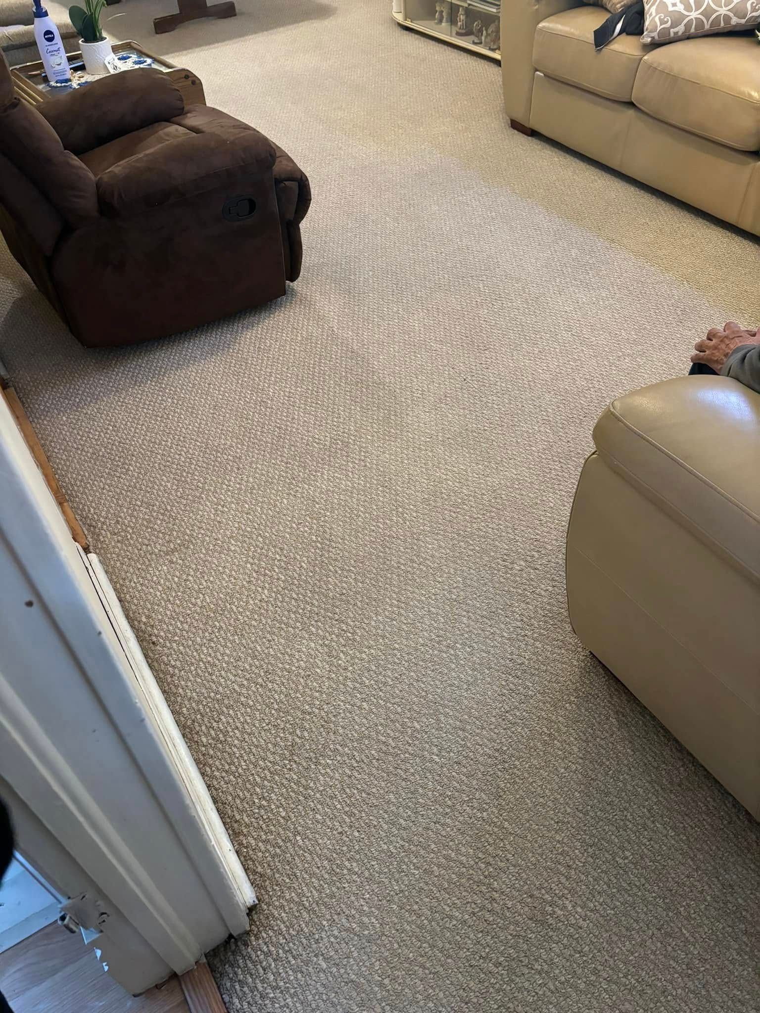 Carpeted living room with brown and beige sofas and a doorway in the foreground