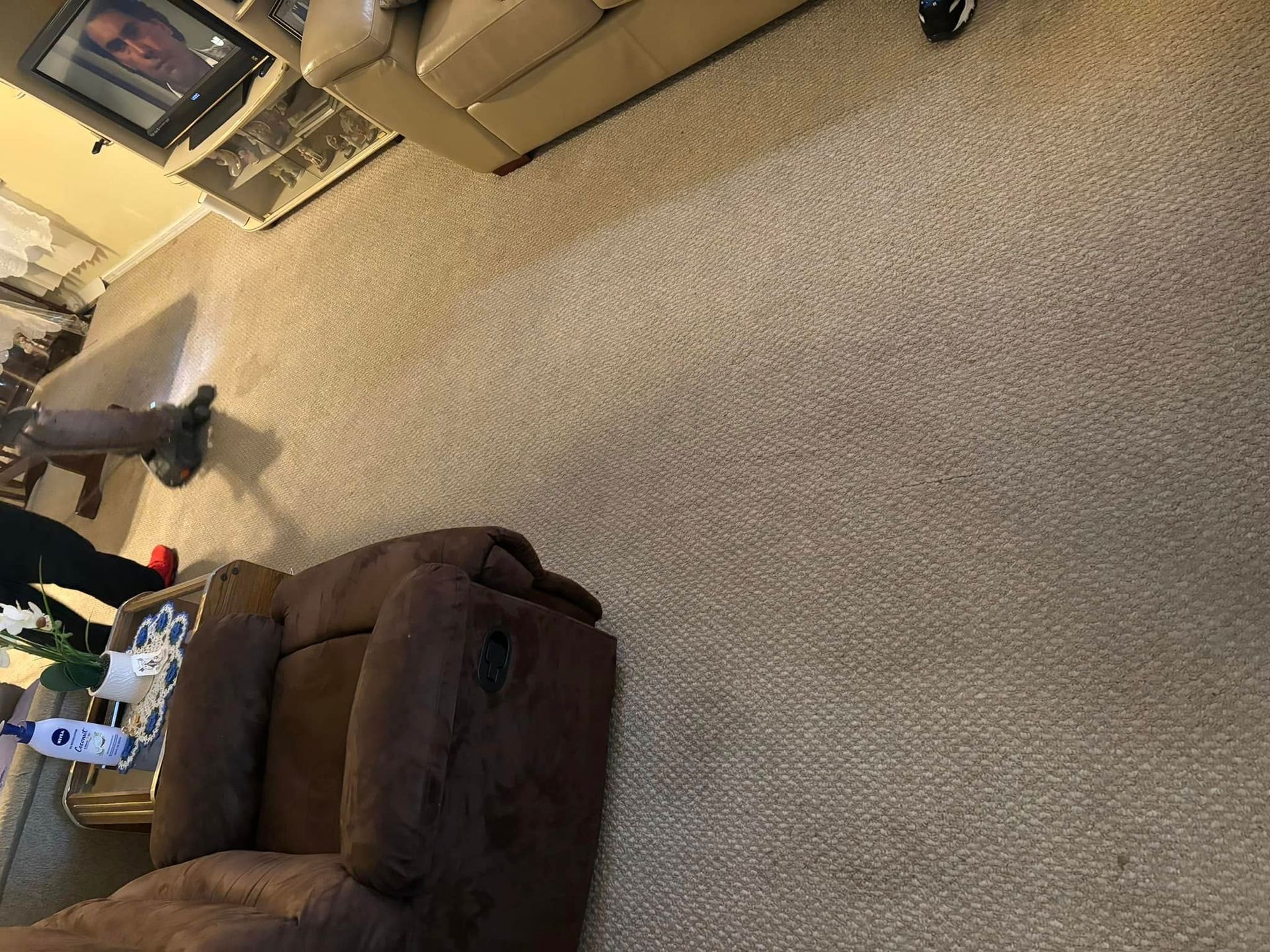 Living room with a beige couch, brown recliner, TV, and beige carpet, rotated sideways