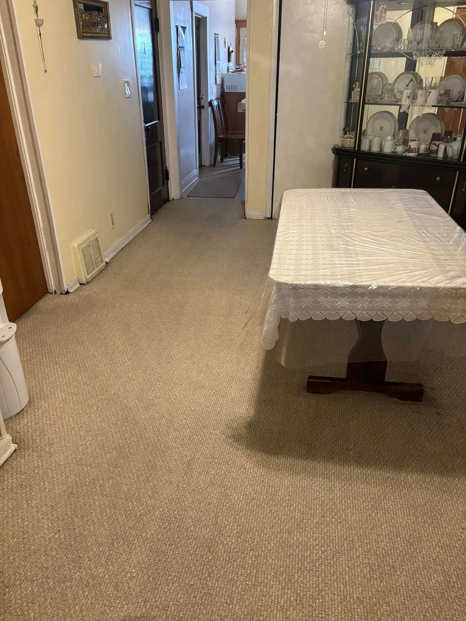 Carpeted hallway with a lace-covered table and glass display cabinet on the right