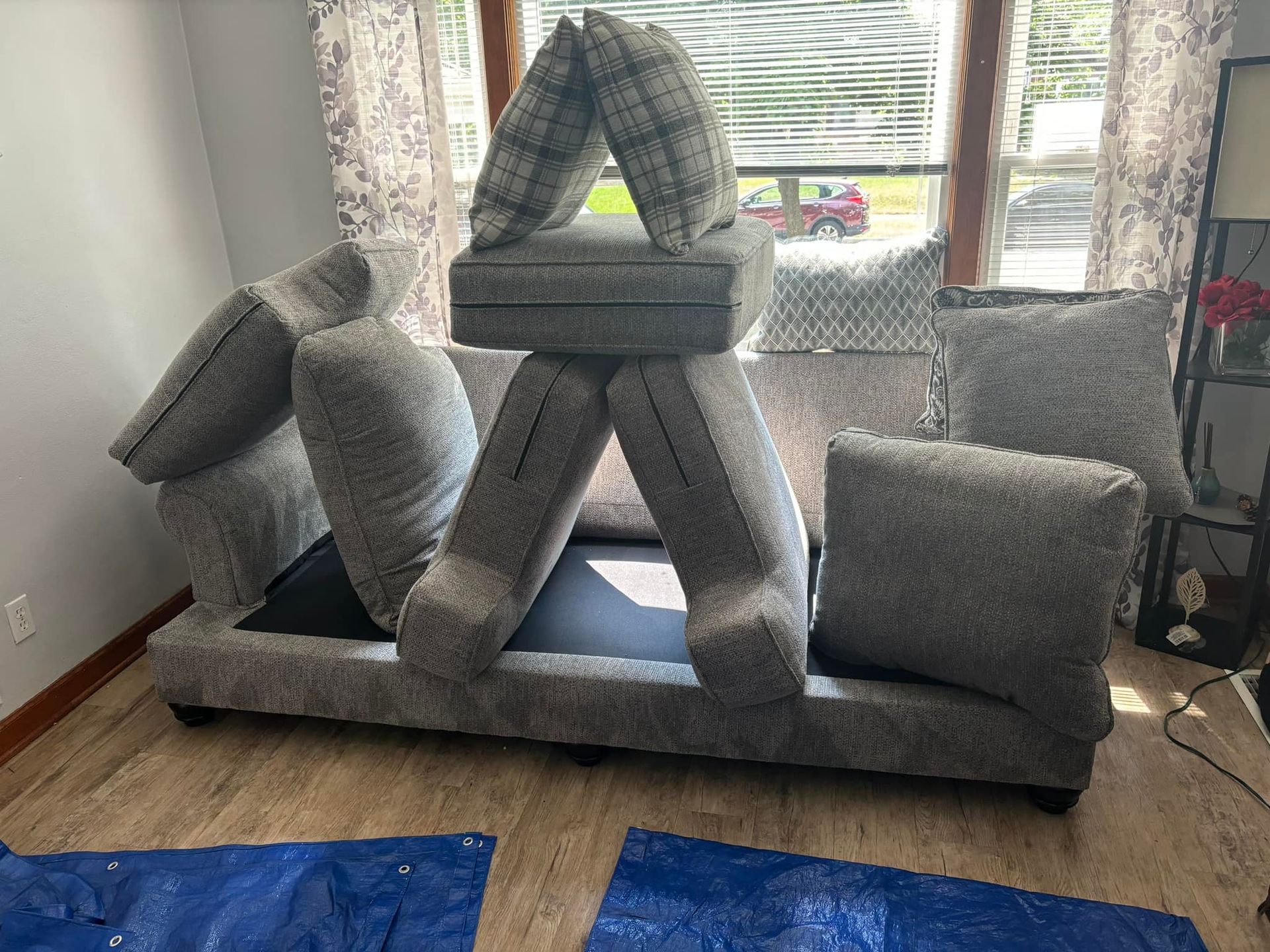 Gray cushion fort structure in a living room, built on a sofa near a window.