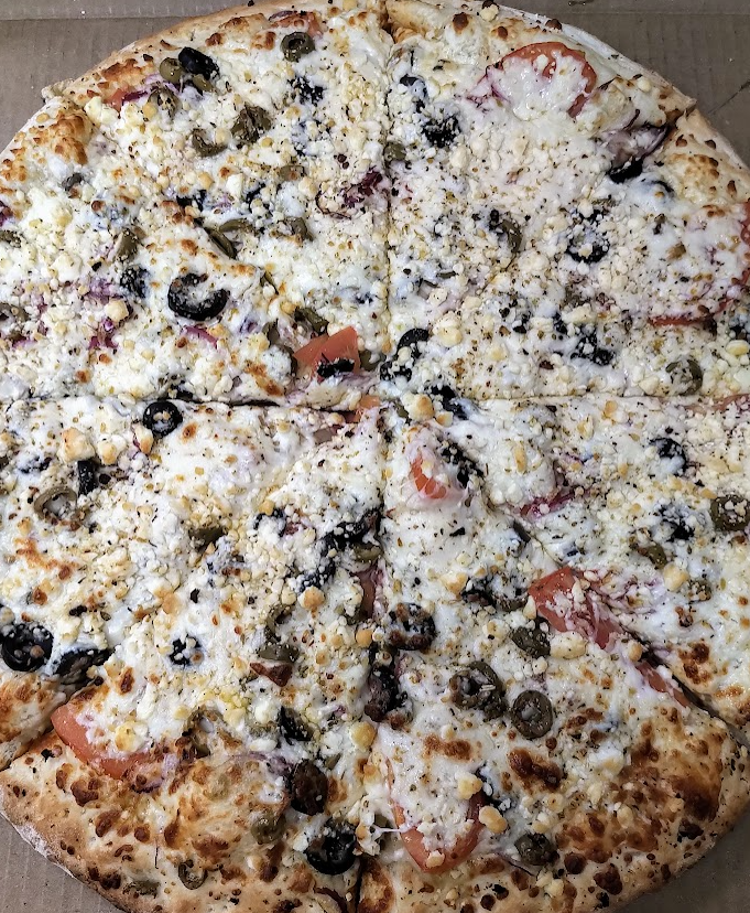 Greek pizza with olives, feta, tomatoes, and capers, cut into slices.