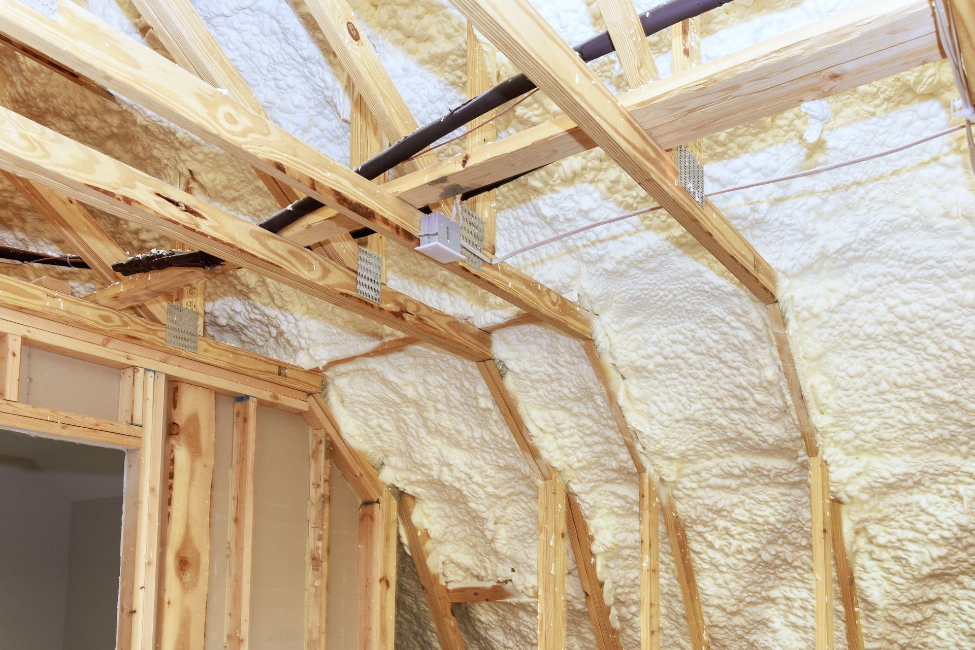 Exposed wood framing and spray foam insulation inside a house under construction