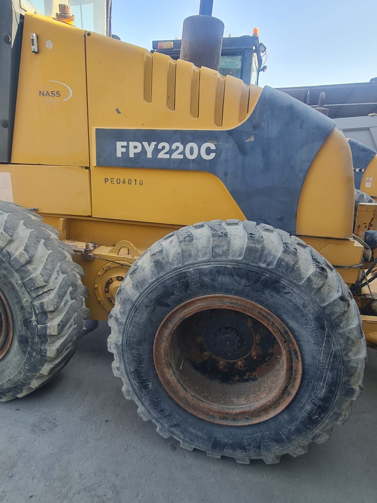 Yellow and dark gray FPY220C motor grader with large tires; close-up view.