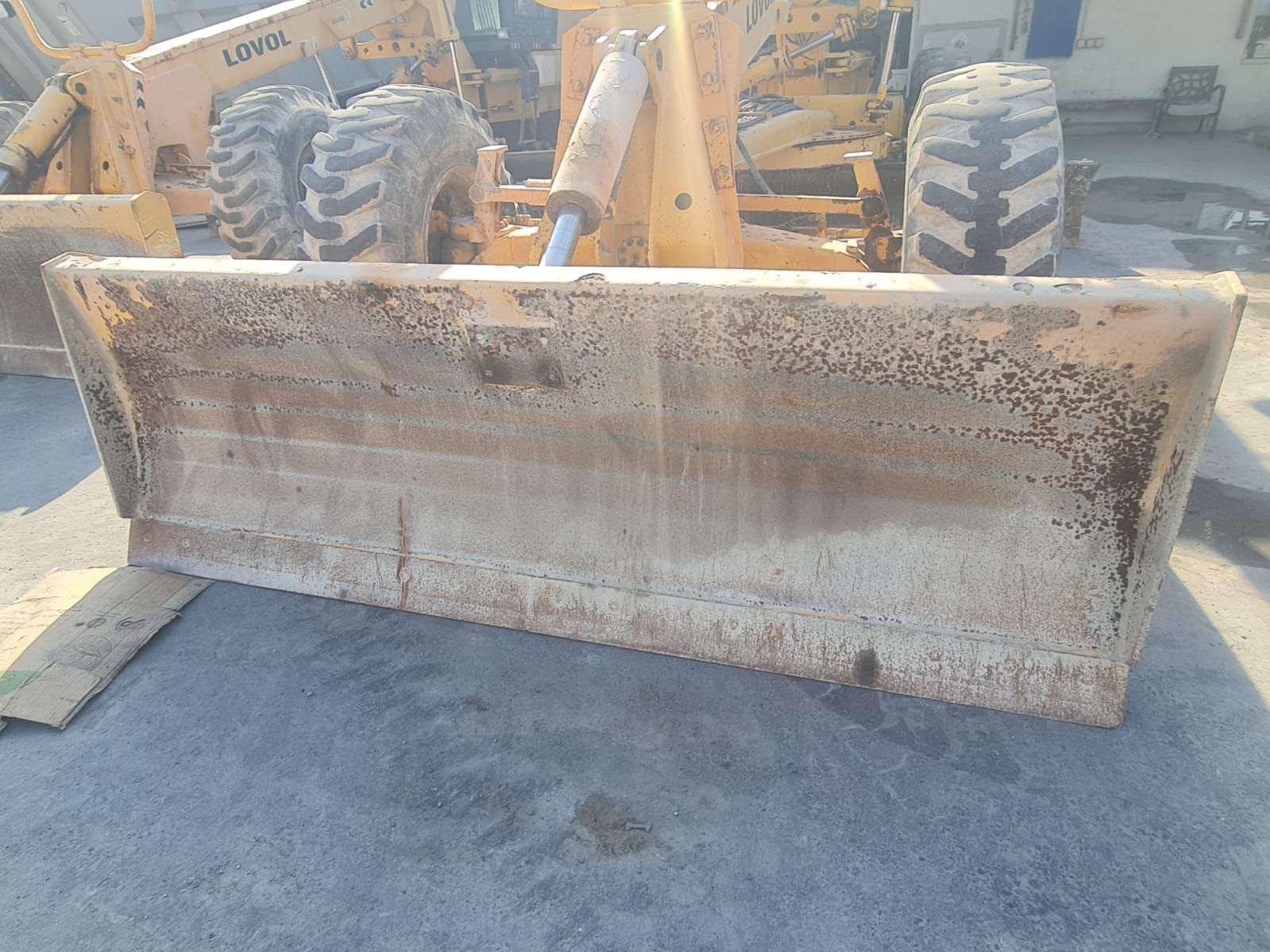 Yellow bulldozer blade covered in dirt, tires in the background.