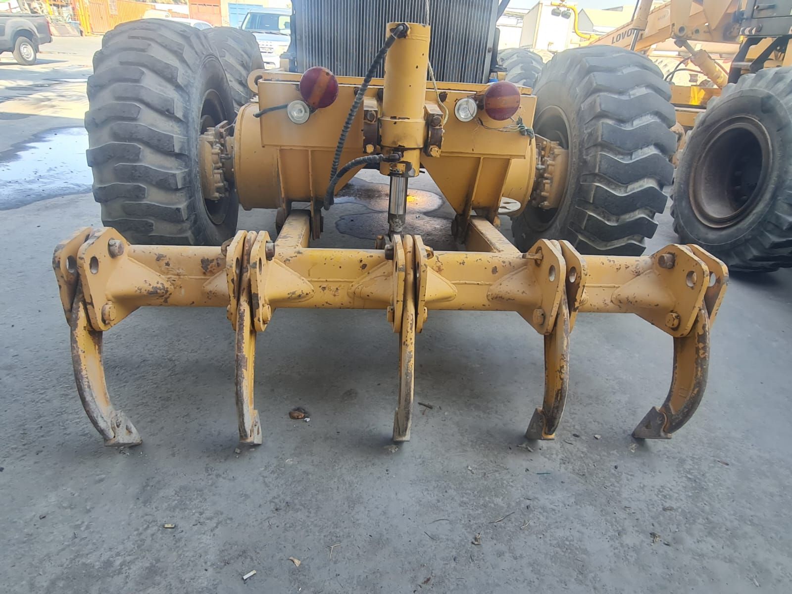 Yellow heavy machinery with claw attachments and large tires, outdoors.