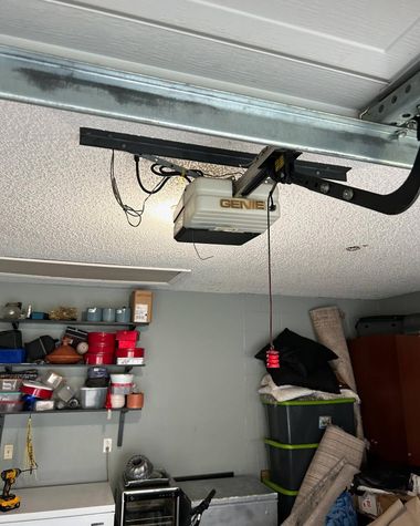 Garage ceiling with an overhead garage door opener and shelves of tools and supplies along the wall