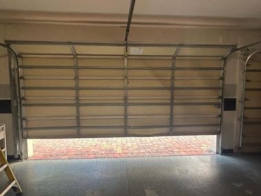 Open garage door with sunlight on the driveway and a rolling table inside.