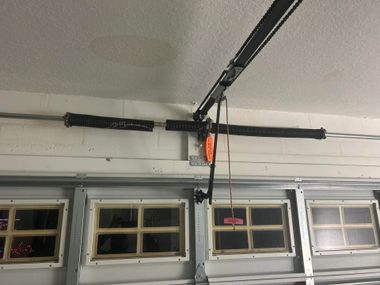 Garage ceiling with overhead door opener rail and four window panels on the door below