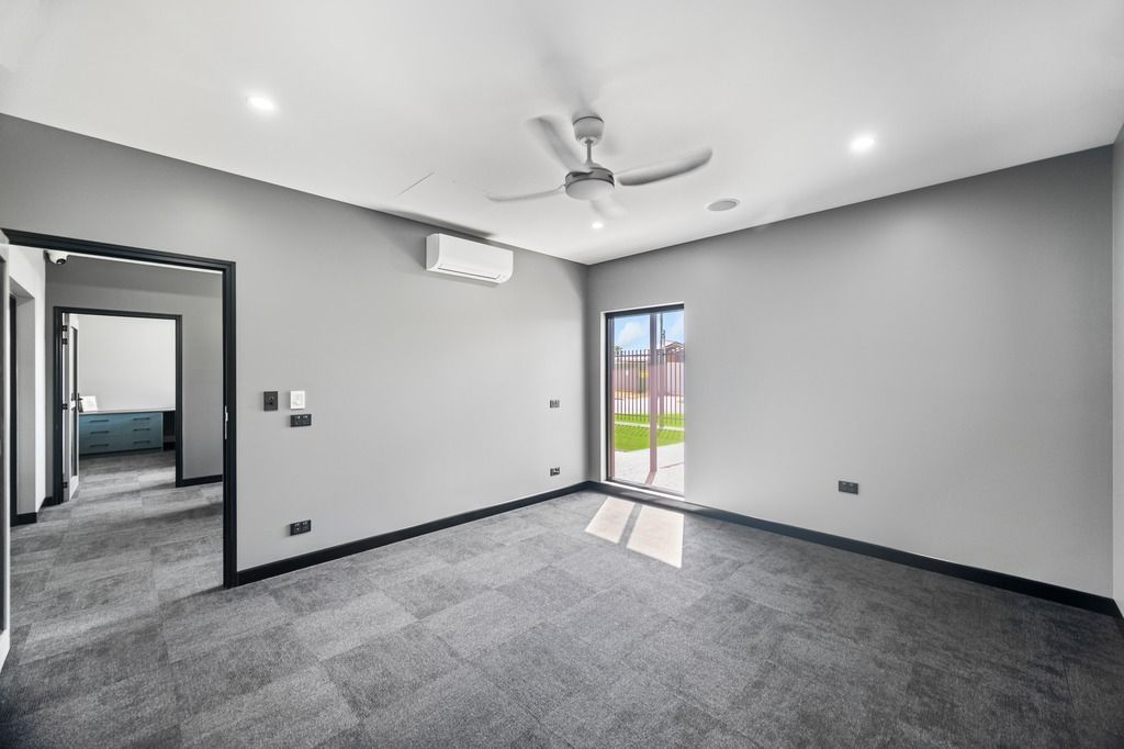 Empty gray room with carpet, sliding door, and open doorway — Construction Company in Townsville, QLD