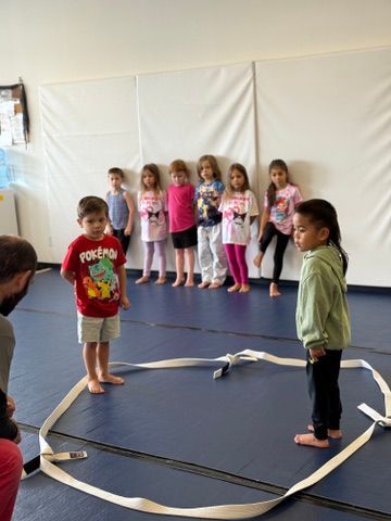 Children standing in a gym area getting ready to play sumo wrestling.