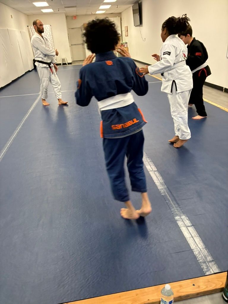 Children practicing martial arts in a dojo, wearing white and blue uniforms on a blue mat.