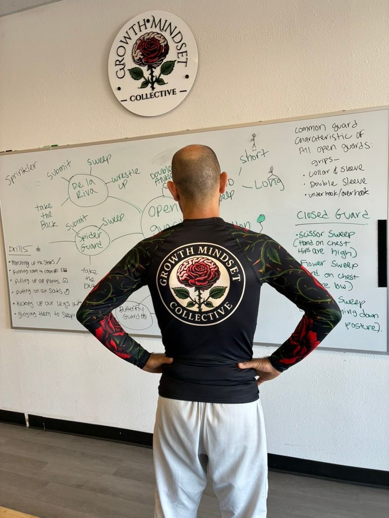 Person standing with hands on hips in front of a whiteboard wall in a gym or training room.