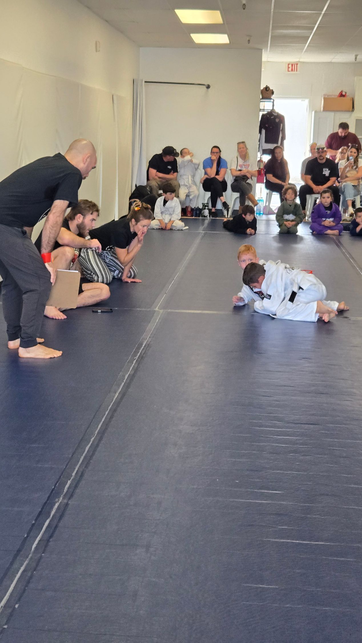 Children crawling in a martial arts studio while an instructor watches from the side