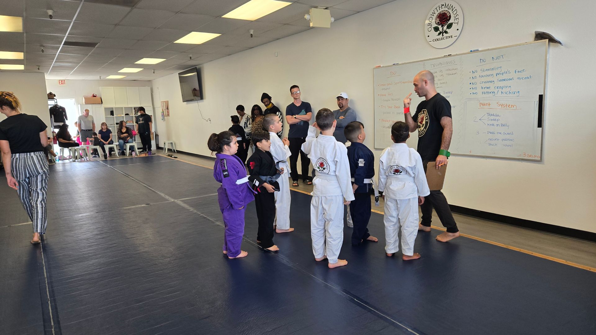Martial arts class with children in gis listening to an instructor in a training studio