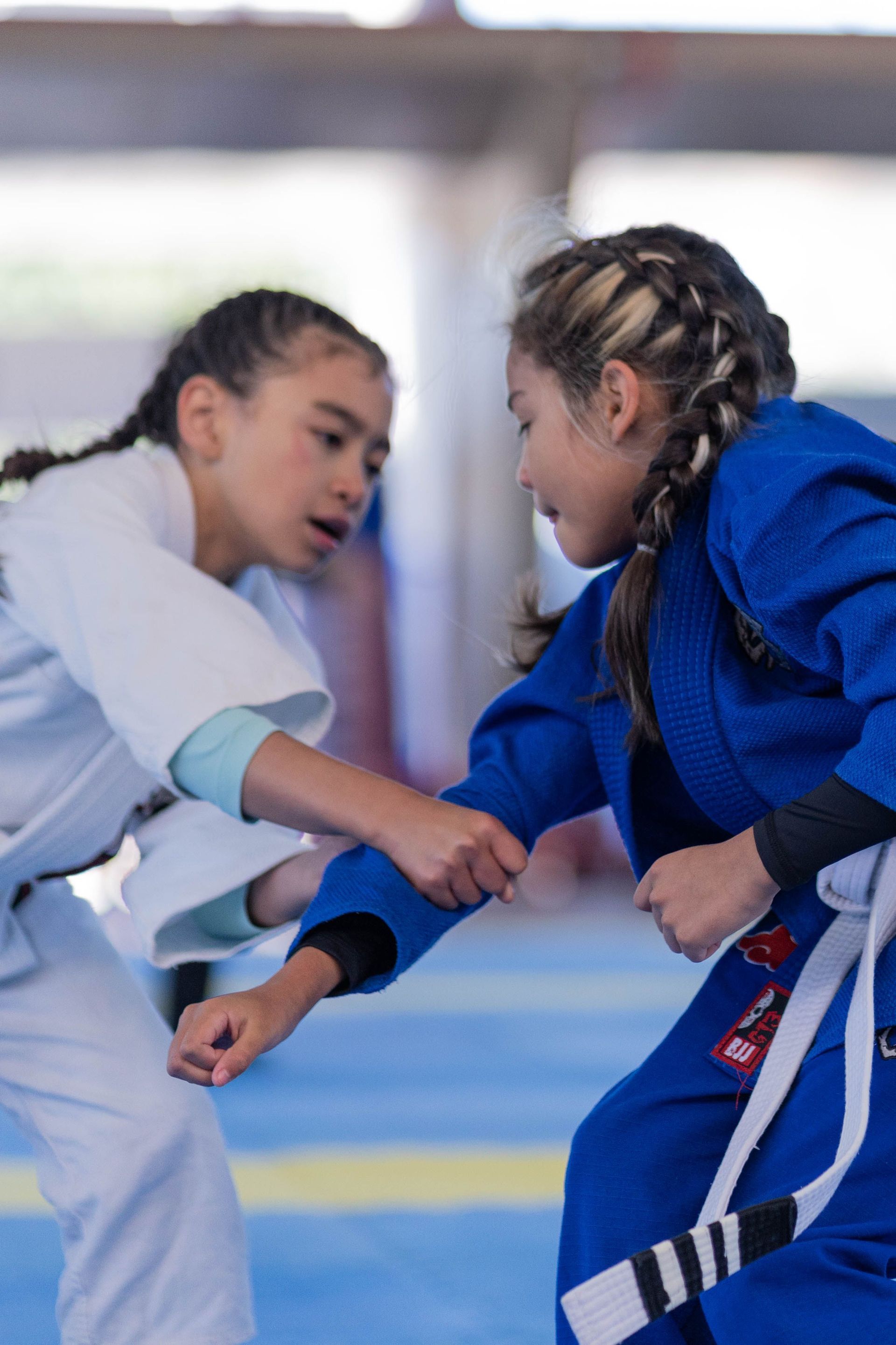Two children in martial arts uniforms practicing a grappling move on a mat
