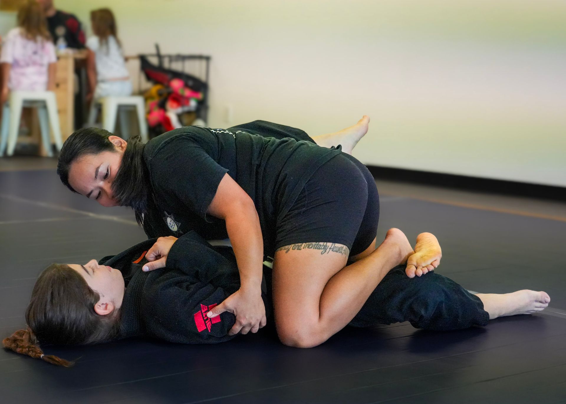 Woman practicing closed guard passing technique during Brazilian Jiu Jitsu training