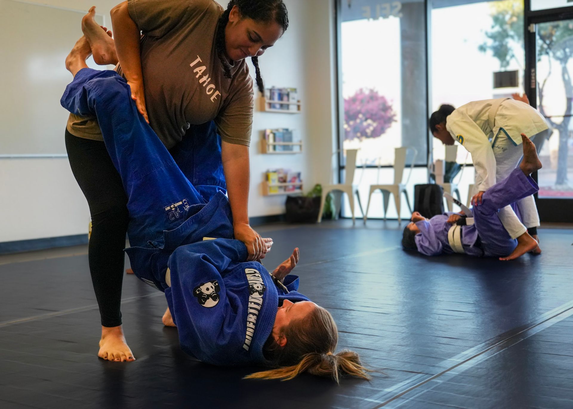 Woman standing to open closed guard during Brazilian Jiu Jitsu training at Growth Mindset Collective