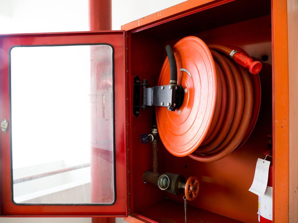 A Fire Hose Is Sitting Inside of A Red Box — Fireline 2000 Fire Equipment Pty Ltd in Browns Plain, QLD