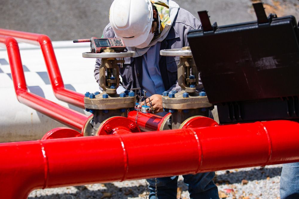A Man in A Hard Hat Is Working on A Red Pipe — Fireline 2000 Fire Equipment Pty Ltd in Browns Plain, QLD