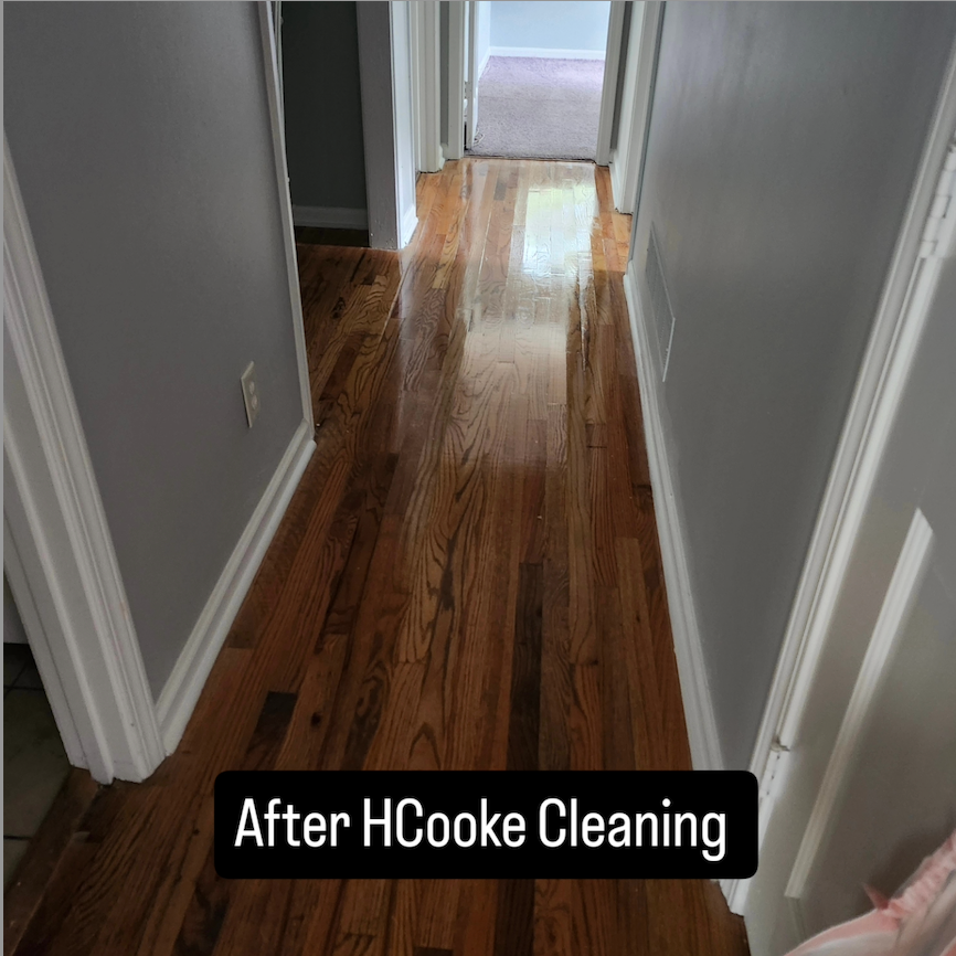 A woman is cleaning a kitchen counter with a cloth and spray bottle.