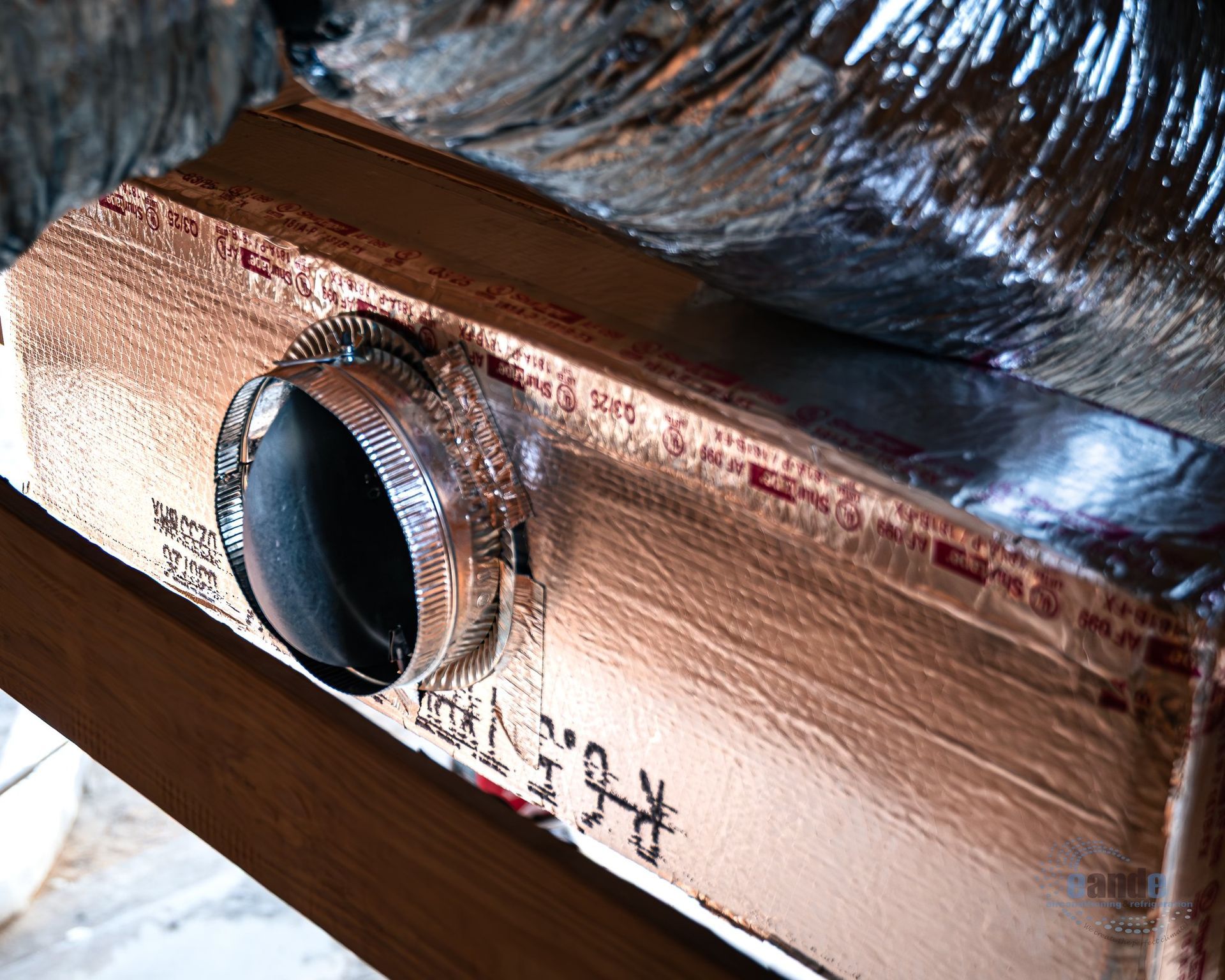 Copper-colored metal box with a black circular knob and foil insulation on top