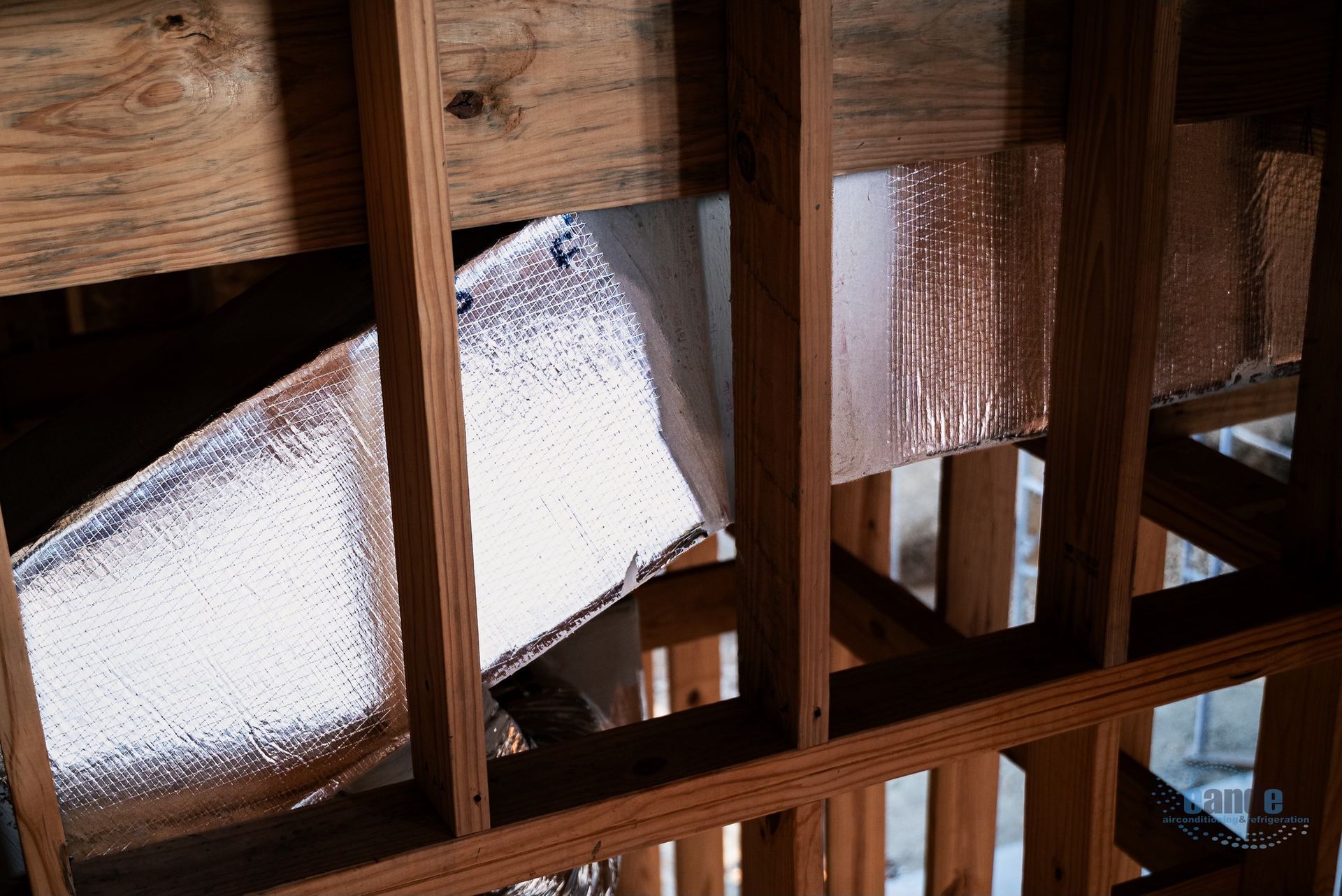 Foam insulation between exposed wooden beams in an unfinished attic ceiling