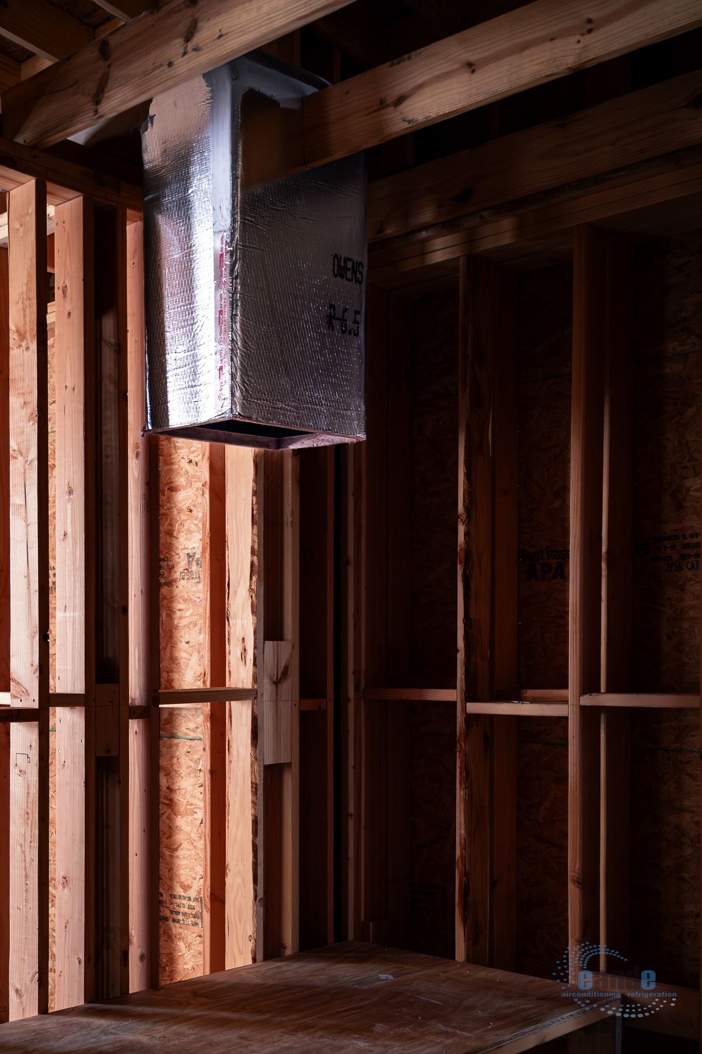 Exposed wooden framing inside a house under construction with a vent pipe and unfinished floor