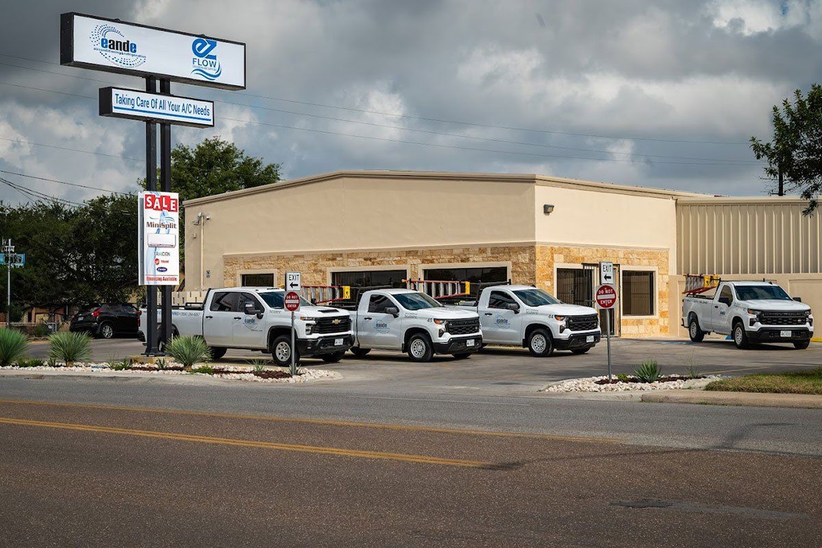 Small beige auto shop with several pickup trucks parked outside on a cloudy day