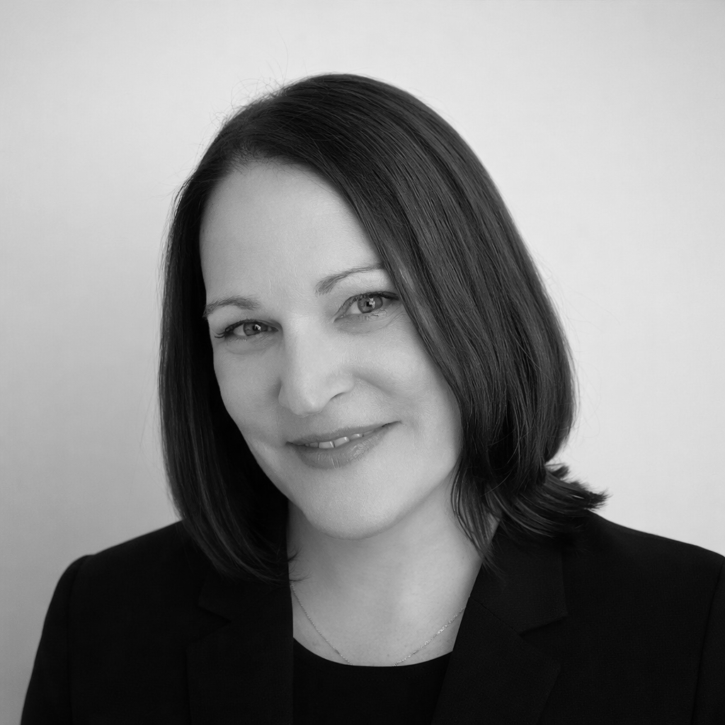 Black-and-white portrait of a smiling woman with shoulder-length dark hair against a plain background