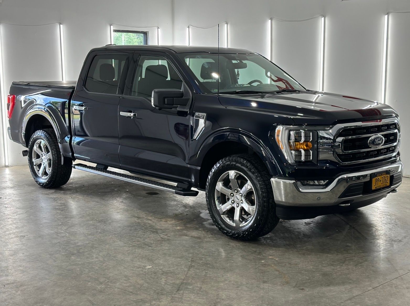 Dark blue Ford F-150 crew cab pickup truck parked in a well-lit indoor garage.