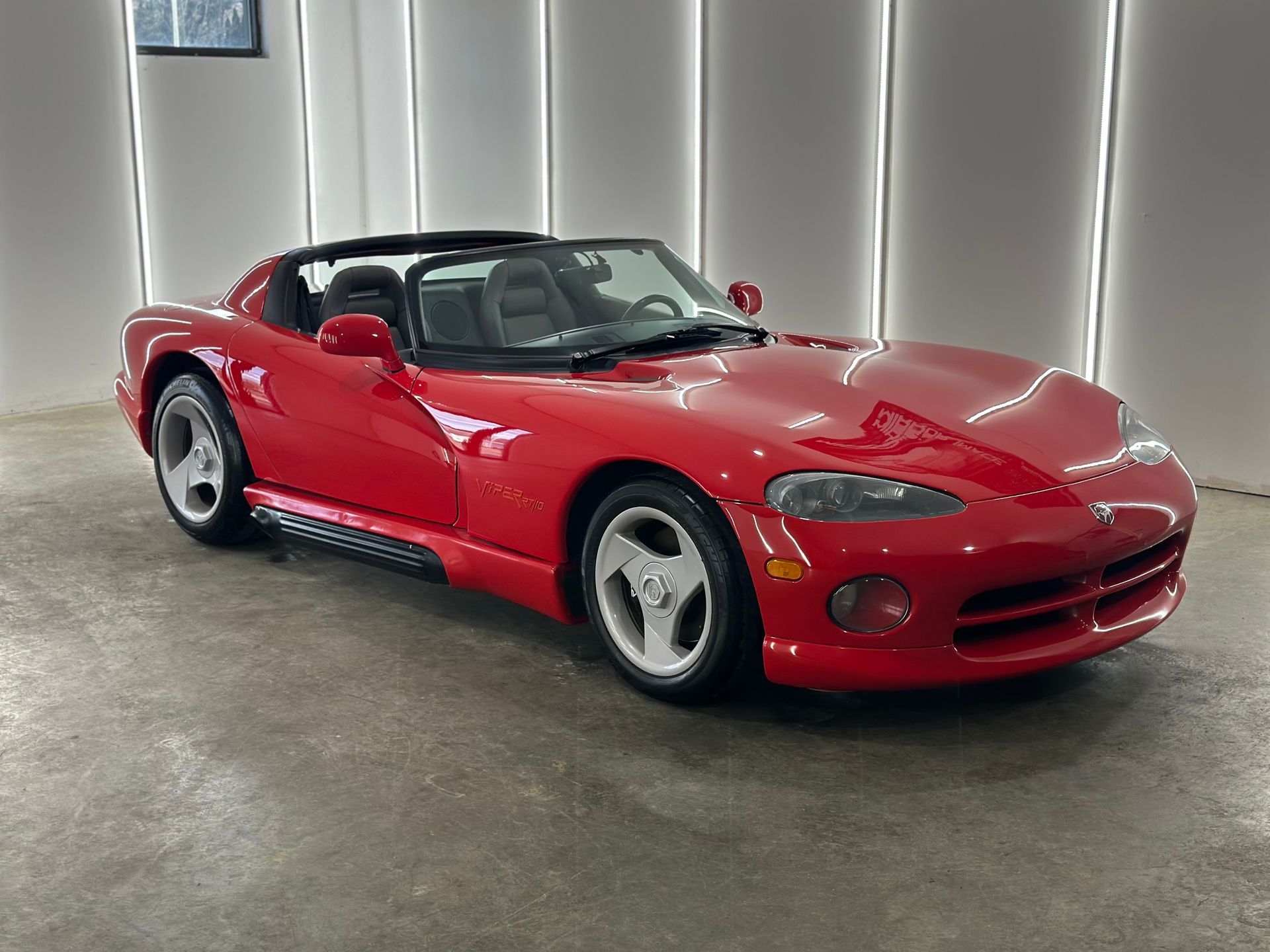 Red Dodge Viper convertible parked in a modern, brightly lit garage.
