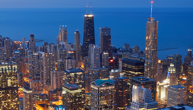 An aerial view of a city at night with a body of water in the background.