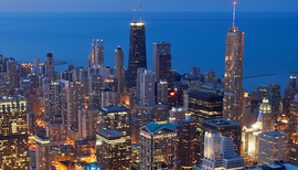 An aerial view of a city at night with a body of water in the background.