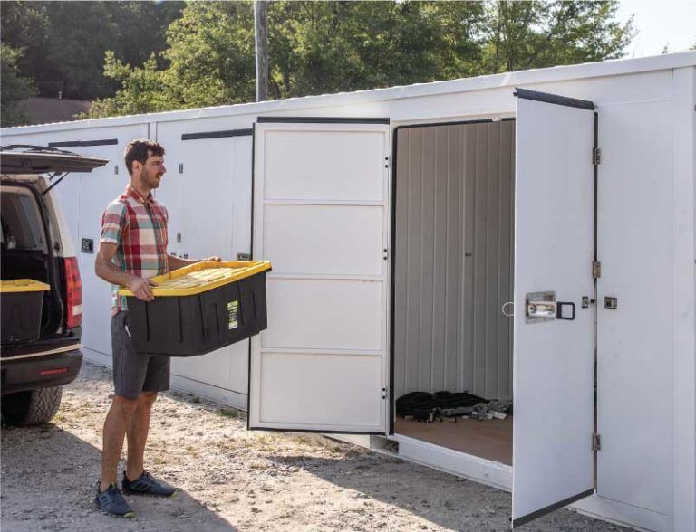 a man is carrying a large black box into a storage container .