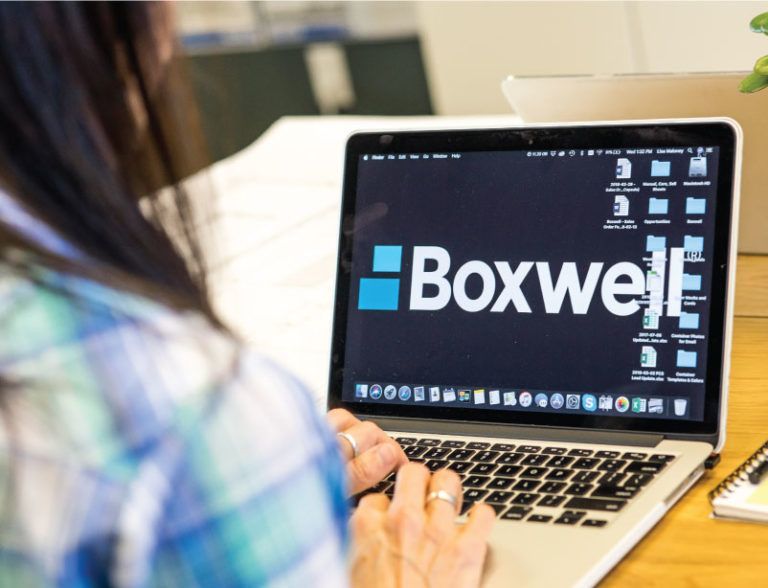 a person is typing on a laptop with the boxwell logo on the screen