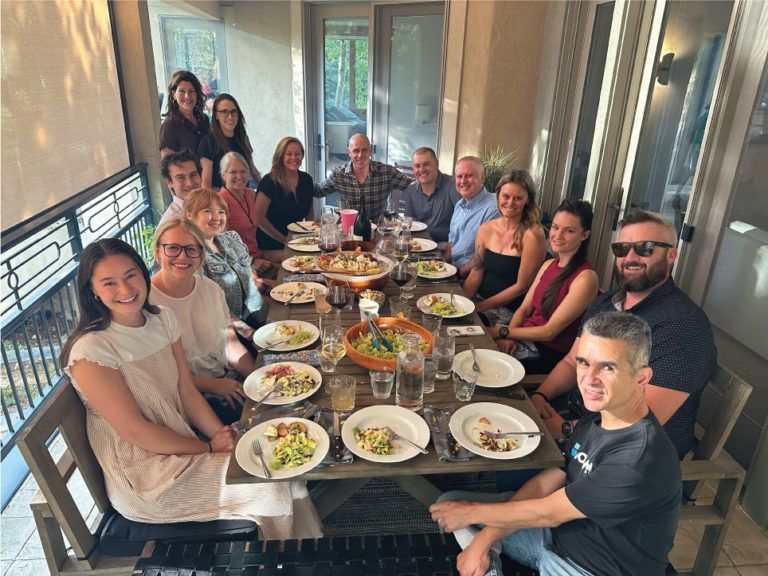 a group of people sitting around a table with plates of food