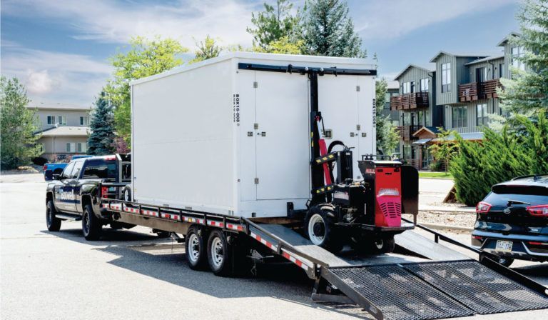 a truck is towing a trailer with a container on it .